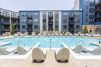 A swimming pool with chaise lounge chairs and a building in the background